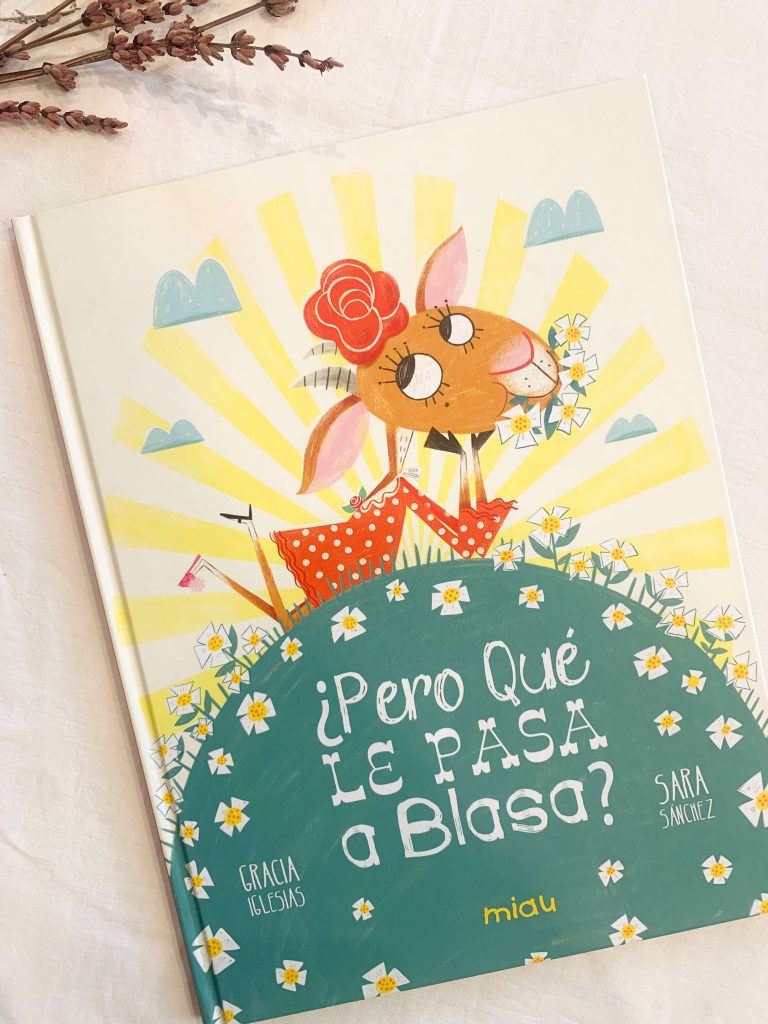 Portada del cuento en el que aparece la cabra Balsa tumbada sobre una colina llena de margaritas