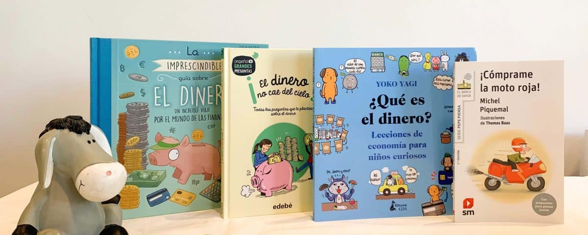 foto en la que aparecen cuatro libros sobre dinero, una hucha y monedas