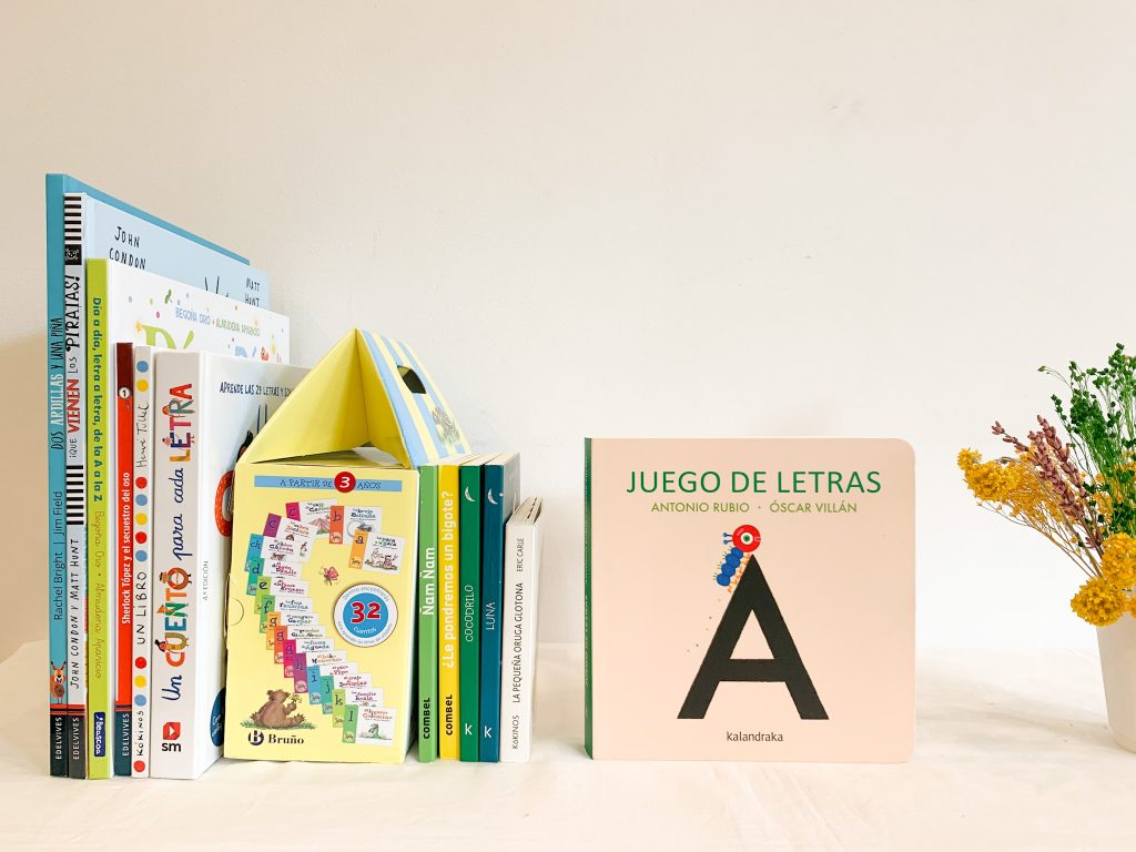 aparecen varios libros de canto y en primer plano el libro juego de letras